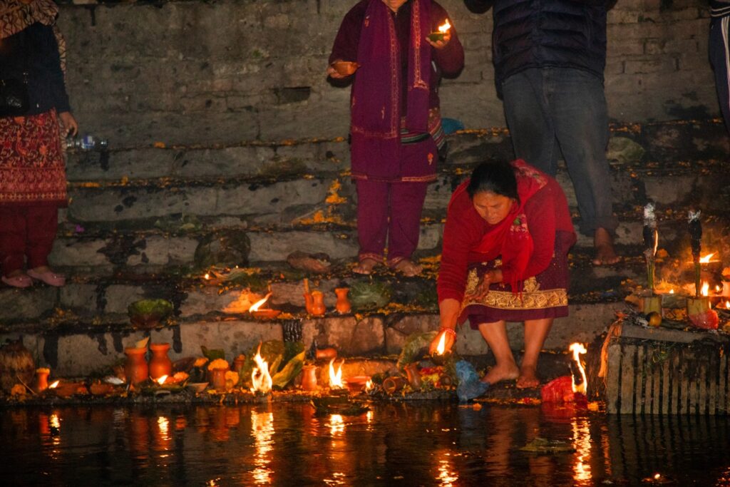 Devotees lighting oil lamps on the riverbank during evening ritual at Pashupatinath Temple, Kathmandu
