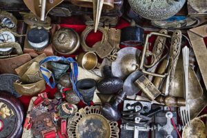 Diverse Collection of Vintage Antiques and Artifacts Displayed at a Local Market - A vibrant assortment of vintage antiques and artifacts is laid out on a market table, showcasing various items including clocks, lock mechanisms, and decorative trinkets. Shoppers explore the unique pieces, each with its own story, while traders engage in lively discussions about the history and craftsmanship behind these collectibles.